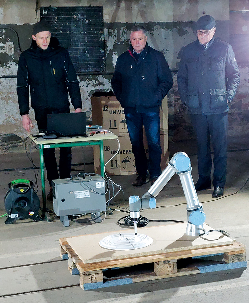 In der zukünftigen Forschungswerkstatt Robotik im Rittergut demonstriert Tobias Zerger (l.) von der TU Dresden die Arbeit des Roboterarms an einem Bauteil.